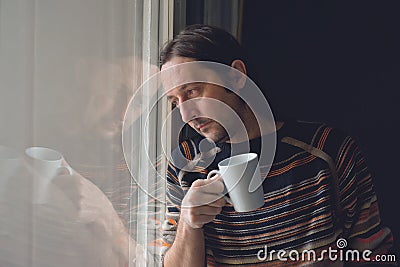 Sad man by the window drinking coffee