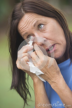 Sad mature woman tissue cleaning tears in eye