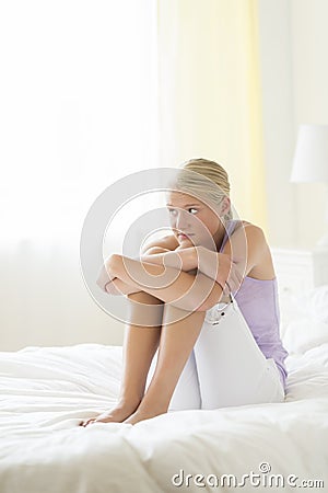 Sad Teenage Girl Hugging Knees On Bed