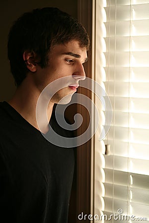 Sad young man looking out window