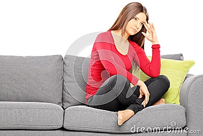 Sad young woman sitting on a modern sofa