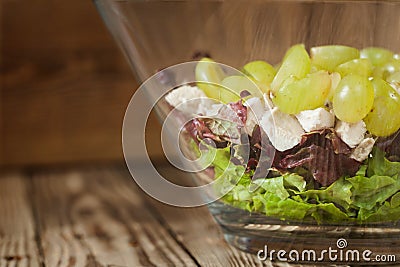 Salad from red and green lettuce leaves with chicken and grapes