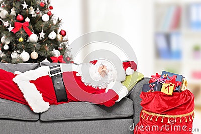 Santa Claus sleeping by a Christmas tree at home