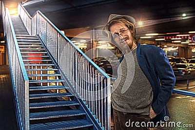 Satisfied funny man by the stairs, underground parking lot background