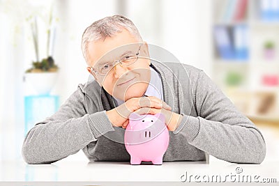 Satisfied gentleman posing over a piggy bank at his home