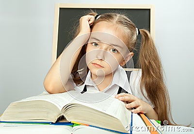 School girl making homework behind stack of books.