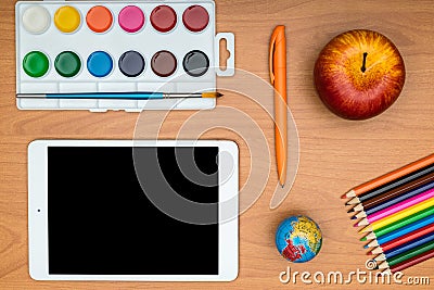 School supplies and tablet on wooden school desk from above