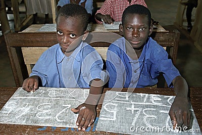 Schoolchildren writing with chalk on a slate