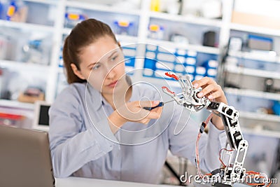 Schoolgirl adjusts robot arm model