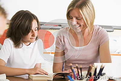 A schoolgirl and her teacher reading in class