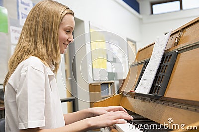 Schoolgirl playing piano in music class