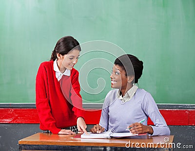 Schoolgirl Pointing On Paper While Teacher Looking