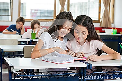 Schoolgirls Studying Together At Desk