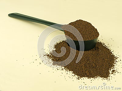 Scoop of fresh ground coffee over pale background