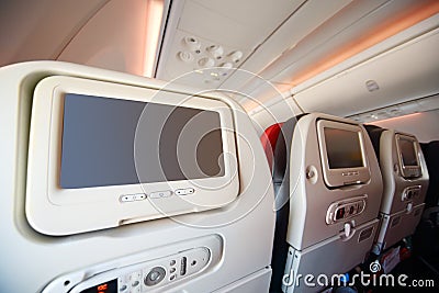 Screens for passengers in back of soft seats in airplane.