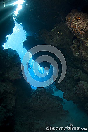 Scuba diver silhouette outside an underwater cave.