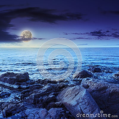 Sea wave breaks about boulders at night