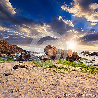 Sea wave breaks about boulders at sunset