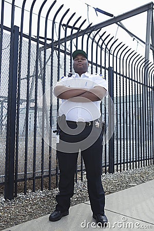 Security Guard Standing In Front Of Prison Fence