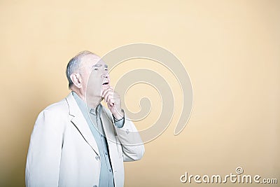 Senior adult man with his hand on his chin looking up inquisitively