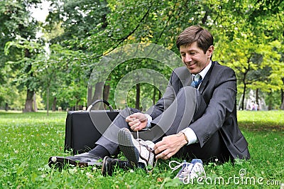 Senior business man changing shoes in park