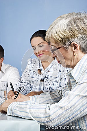 Senior business woman writing at meeting