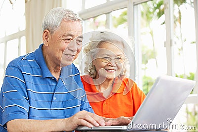 Senior Chinese Couple Using Laptop At Home