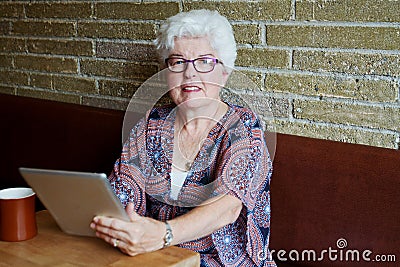 Senior in coffee shop with tablet