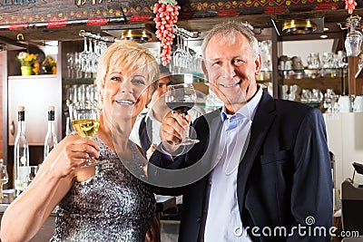 Senior couple at bar with glass of wine in hand