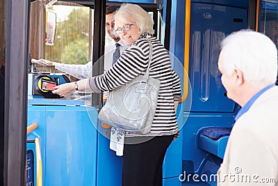 Senior Couple Boarding Bus And Using Pass