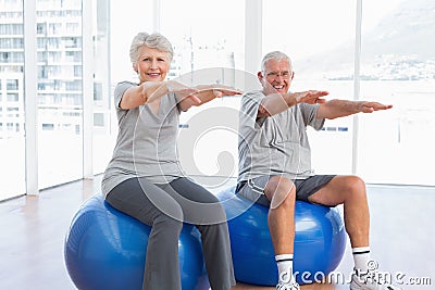 Senior couple doing stretching exercises on fitness balls