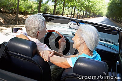 Senior couple driving in sports car