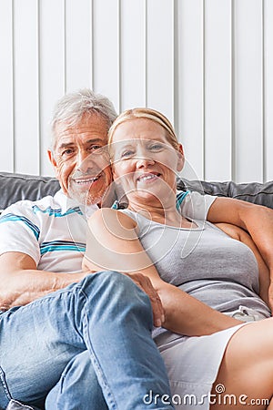 Senior couple embrace sitting on sofa smile