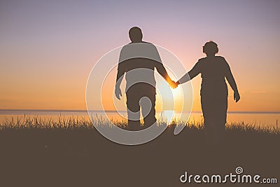 Senior couple holding hands silhouettes