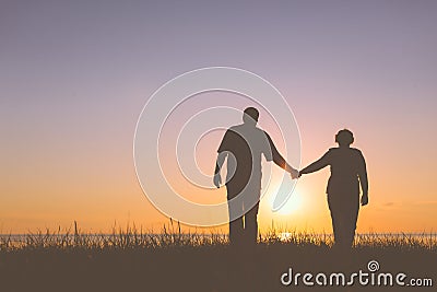 Senior couple holding hands silhouettes
