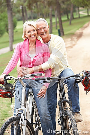 Senior couple riding bicycle in park