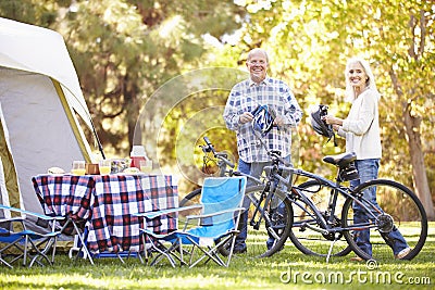 Senior Couple Riding Bikes On Camping Holiday