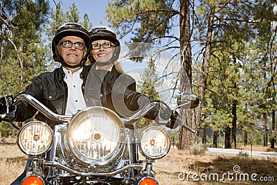 Senior couple riding motorcycle through a forest