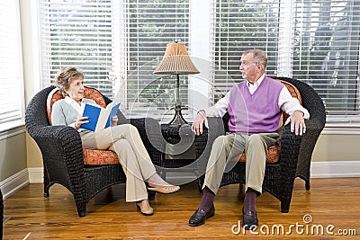 Senior couple sitting on living room chair reading