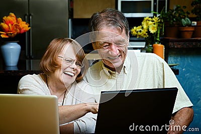 Senior couple using laptop computers at home