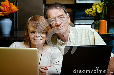 Senior couple using laptop computers at home