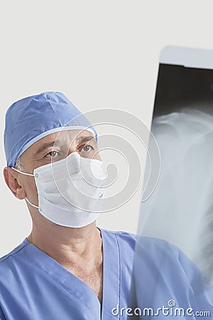 Senior male surgeon examining x-ray over gray background