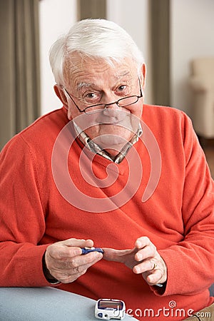 Senior Man Checking Blood Sugar Level At Home