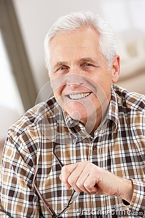 Senior Man With Glasses Relaxing In Chair At Home