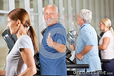 Senior man holding thumbs up in gym