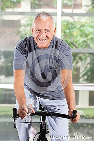 Senior man on home trainer in gym