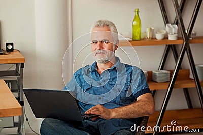Senior man with notebook sitting at the kitchen