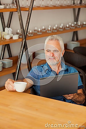 Senior man with notebook sitting at the kitchen an