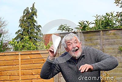 Senior man playing with paper airplane.