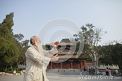 Senior Man Practicing Tai Ji in Front of Traditional Chinese Building